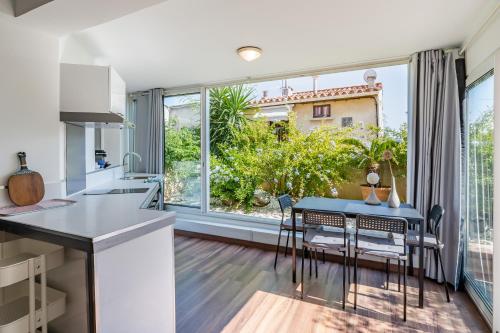 une cuisine avec une table et des chaises ainsi qu'une grande fenêtre dans l'établissement Rose d'Eden par Dodo-a-Cassis, à Cassis