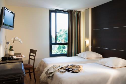 ein Hotelzimmer mit einem Bett und einem Fenster in der Unterkunft Escale Oceania Rennes Cap Malo in La Mézière