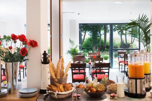 a table topped with bowls of food and orange juice at Escale Oceania Rennes Cap Malo in La Mézière