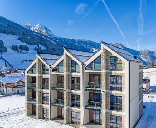 an apartment building in the snow with mountains in the background at Bergparadies - inklusive Eintritt in die Alpentherme in Dorfgastein