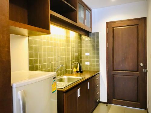 a small kitchen with a sink and a wooden door at Baan Khun Nine in Pattaya Central