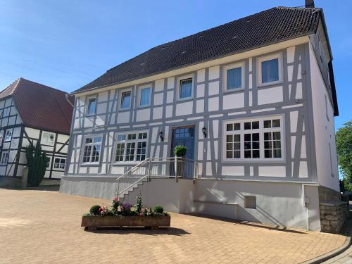a white and gray building with a porch and flowers at Gestorfer Kötnerhof Business und Landlust in Springe