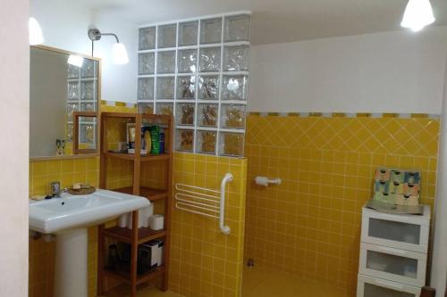 ein Badezimmer mit einem Waschbecken und einer gelben Kachelwand in der Unterkunft Lugares Comunes. Poyales. in Poyales