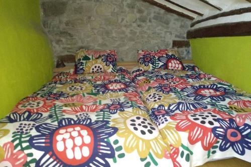 ein Bett mit einer bunten Tagesdecke mit Blumen darauf in der Unterkunft Lugares Comunes. Poyales. in Poyales