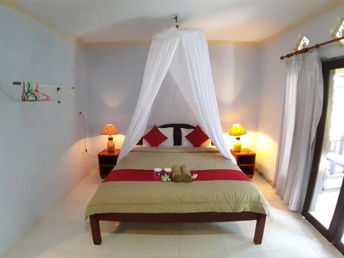a bedroom with a bed with a canopy at Mangga homestay Gili air in Gili Air