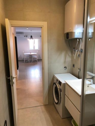 a kitchen with a washing machine and a table at Apartman Linda in Cres