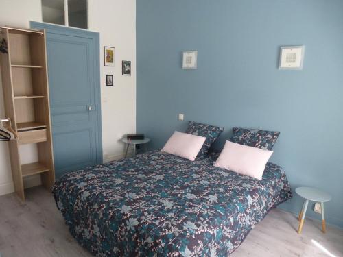ein blaues Schlafzimmer mit einem Bett mit zwei rosa Kissen in der Unterkunft JOANN in Wimereux