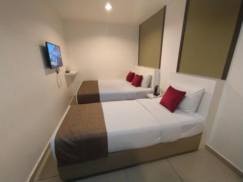 a hotel room with two beds with red pillows at Crescendo Boutique Hotel in Nusajaya