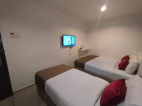 a hotel room with two beds and a tv on the wall at Crescendo Boutique Hotel in Nusajaya