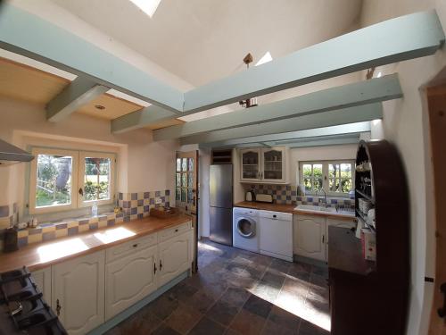 une grande cuisine avec des placards blancs et un plafond bleu dans l'établissement Les Rivieres, à Saint-Germain-sur-Sèves