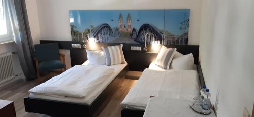 2 Betten in einem Zimmer mit weißer Bettwäsche und Kissen in der Unterkunft Hotel Bären Garni in Freiburg im Breisgau