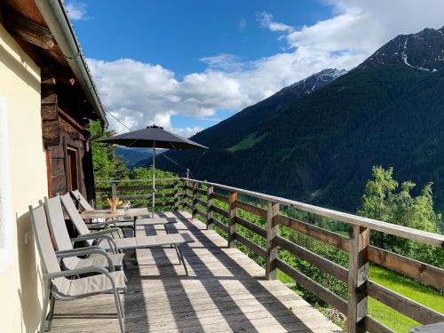 una terraza con sillas, sombrilla y montañas en Badstube Lex, en Großkirchheim