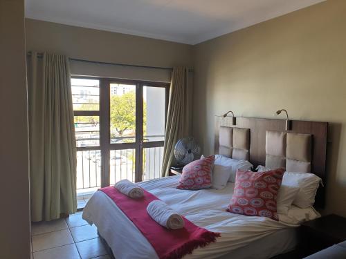 um quarto com uma cama com almofadas e uma janela em Grosvenor Apartments em Pretoria