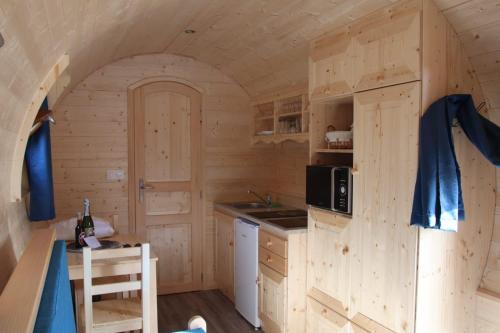 - une cuisine dans une cabane en rondins avec un évier et un four micro-ondes dans l'établissement L'Insolite Jurassienne, à Dompierre-sur-Mont