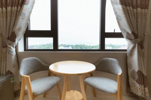 a table and two chairs in a room with windows at Lam Kiều Hotel in Vung Tau