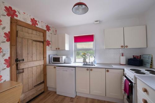 una cocina con armarios blancos y una puerta en Martinshouse Holiday Cottage en Hawick