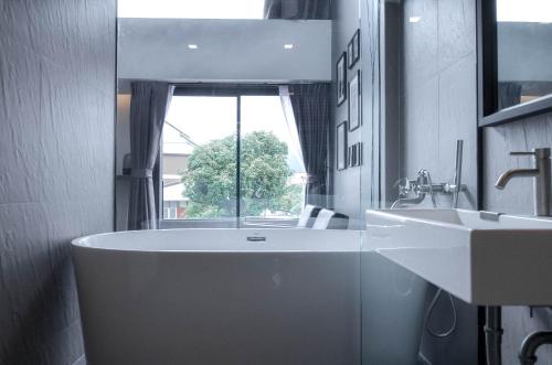 a bathroom with a tub and a sink and a window at CREW Hotel in Chiang Mai