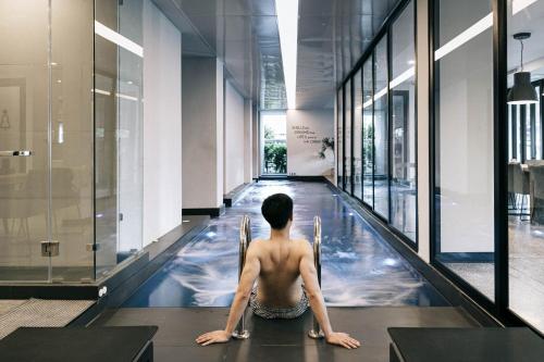 a man sitting in an indoor swimming pool in a building at CREW Hotel in Chiang Mai