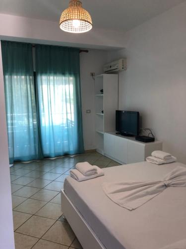 biała sypialnia z łóżkiem i telewizorem w obiekcie Seaward Holiday Home w mieście Dhërmi