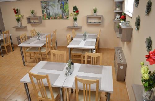 a restaurant with white tables and chairs and flowers at Alfr&eacute;d Panzi&oacute; in Budapest