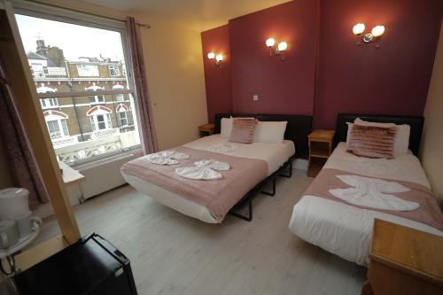 ロンドンにあるホーランド イン ホテルのベッド2台と窓が備わるホテルルームです。