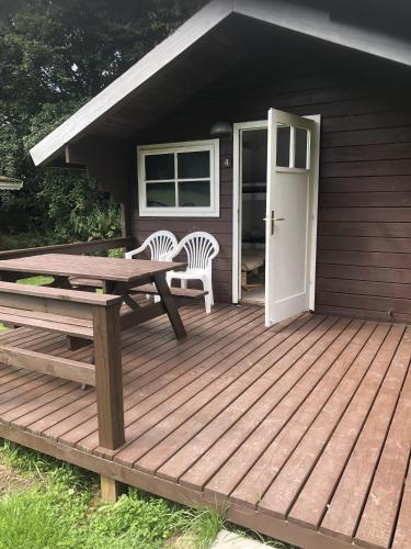 a wooden deck with a table and chairs and a door at Lohals camping in Tranekær