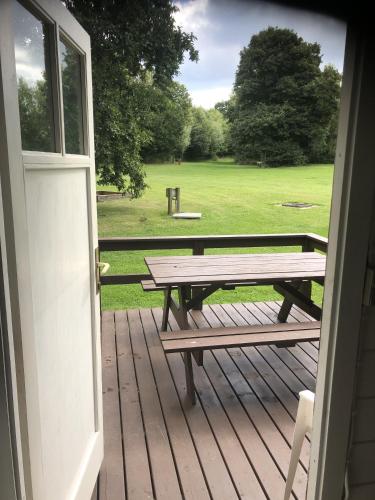a wooden deck with a picnic table and a field at Lohals camping in Tranekær