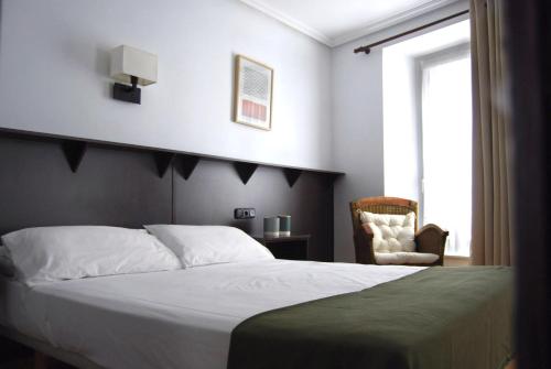 1 dormitorio con 1 cama, 1 silla y 1 ventana en Hotel Arrasate, en Arrasate - Mondragón