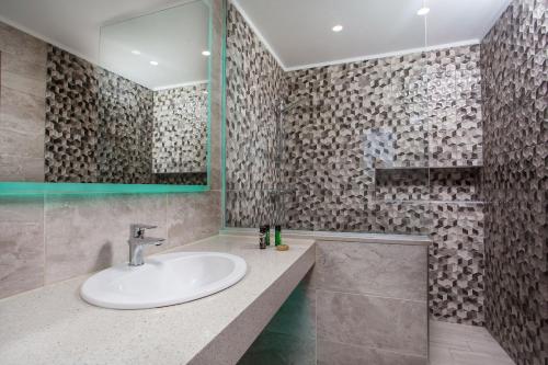 ein Bad mit einem Waschbecken und einem Spiegel in der Unterkunft Platoni Elite in Ialyssos