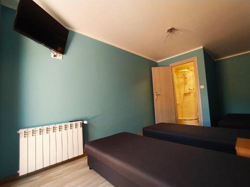 een kamer met 2 bedden en een tv aan de muur bij Pokoje Mira in Torzym