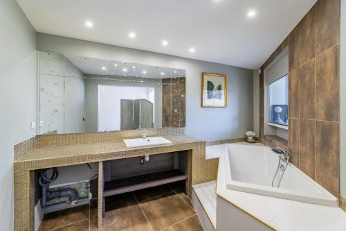 une salle de bain avec un lavabo, une baignoire et un miroir dans l'établissement Rose d'Eden par Dodo-a-Cassis, à Cassis