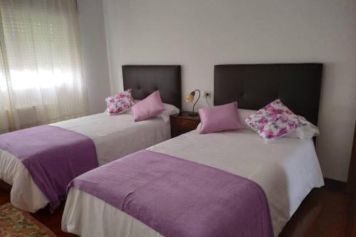 2 camas en una habitación con almohadas moradas y rosas en Milanabonita en Monforte de Lemos