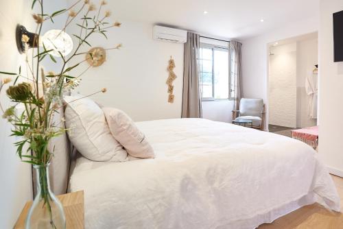 a bedroom with a white bed and a vase with flowers at Maison 1634 - Climatisation, piscine, parking, centre ville, petit-dejeuner compris in Pézenas