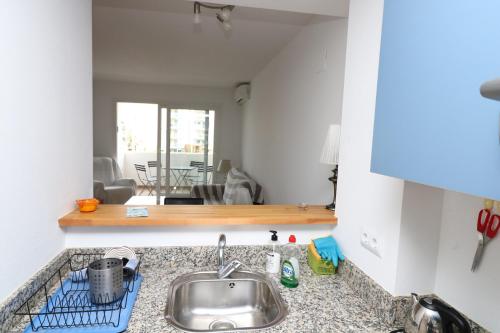 a kitchen counter with a sink and a living room at R. MARINE II (231) in Roses