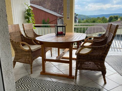 a wooden table with chairs and a lantern on a balcony at Ferienwohnung am Obstgarten in Bad Bocklet