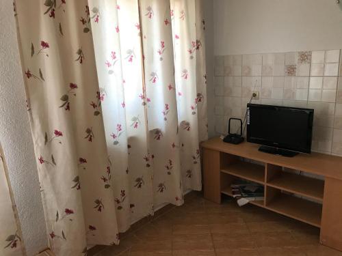 um quarto com uma secretária com uma televisão e uma cortina com borboletas em Apartments Nena em Lozovac