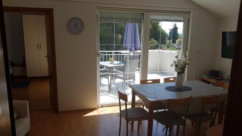 a dining room with a table and chairs and a clock at Apartments Luna in Sveti Filip i Jakov