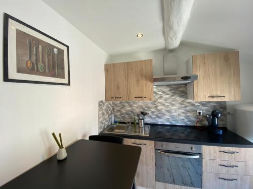 une cuisine avec un comptoir noir et des placards en bois dans l'établissement 018 CHIC & COSY F1 41m2 HYPERCENTRE WIFI SMART TV NETFLIX, à Saint-Étienne