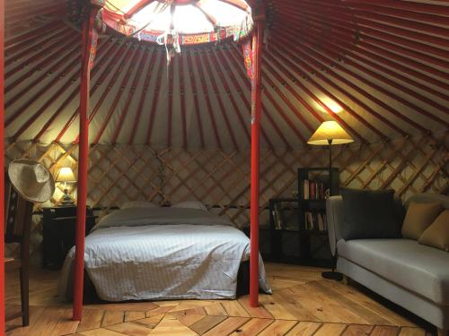 a bedroom in a yurt with a bed and a couch at Moulin de la Buade in Termes