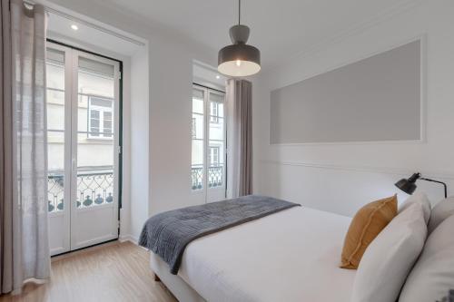 a white bedroom with a bed and a window at Grand Chiado in Lisbon