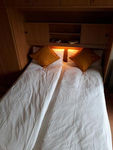 two beds in a room with white sheets and yellow pillows at Wattwurm in Wangerooge
