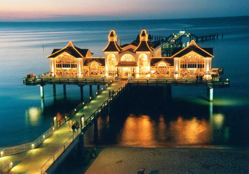 a pier with a large building on the water at night at Appartementhaus Greta im Ostseebad in Ostseebad Sellin