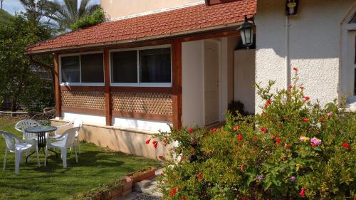 a house with a table and chairs in the yard at Jordan Valley one room apartment in Menaẖemya