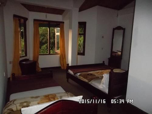 two beds in a room with a mirror and windows at Panorama Accommodations Nuwara Eliya in Nuwara Eliya