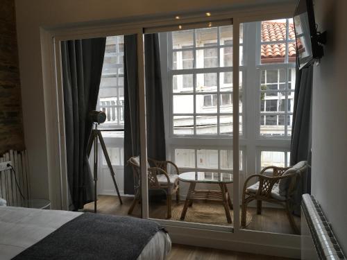 a bedroom with a large window with a view of a city at Hotel A Falúa in Puentedeume