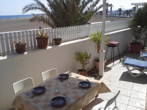 ein Tisch mit blauen Tellern und Stühlen und ein Strand in der Unterkunft Villa Mela in Playa Honda
