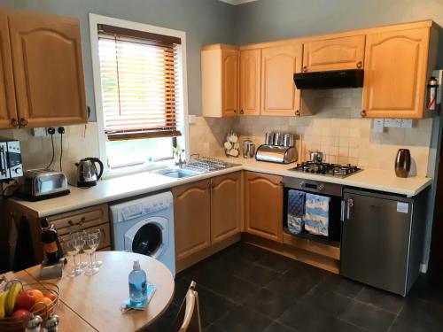 a kitchen with wooden cabinets and a sink and a table at Benside Cottage in Stornoway