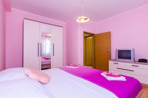 a pink bedroom with a bed and a tv at Villa Mateo with Private Pool in Gruda