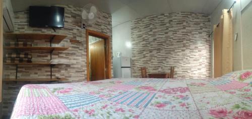 1 dormitorio con cama y pared de ladrillo en Habitación Dalian, en Termas de Guaviyú