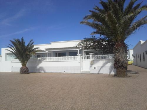 ein weißes Haus mit zwei Palmen davor in der Unterkunft Villa Mela in Playa Honda
